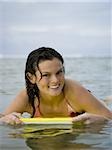 Portrait of a teenage girl floating on a boogie board in the sea