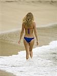 Rear view of a young woman walking on the beach