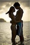 Young couple kissing at sunset in the ocean