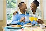 Senior man and a senior woman smiling at the breakfast table