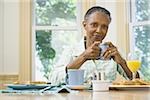 Porträt einer leitenden Frau hält eine Tasse Kaffee am Frühstückstisch