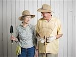 Portrait d'un standing de couple de personnes âgées avec outils de jardinage