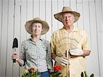 Portrait d'un standing de couple de personnes âgées avec outils de jardinage