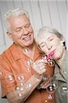 Nahaufnahme, ein älteres Ehepaar bläst Seifenblasen mit einem Seifenblasen