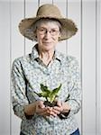 Eine ältere Frau hält eine Pflanze Porträt