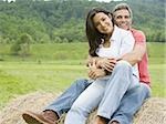 man and a woman sitting on a hay bale