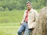 Portrait of a man leaning against a hay bale