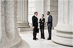 Three lawyers talking in front of a courthouse