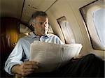 Low angle view of a businessman reading a newspaper in an airplane