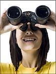Close-up of a young woman looking through a pair of binoculars