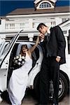 Groom kissing his bride's hand and getting out of a car