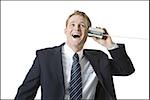 Portrait of a businessman using a tin can phone