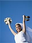 Portrait of a bride holding a bouquet of flowers and a pair of sandals