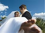 Low angle view of a young man carrying his bride and smiling