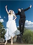 Low angle view of a newlywed couple holding hands and jumping