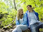 Close-up of a young couple sitting in the forest and smiling