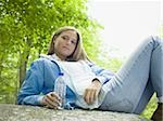 Portrait d'une jeune femme allongée sur un rocher et tenant une bouteille d'eau