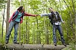 Low angle view of a young couple holding hands and walking on a fallen tree
