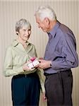 Rear view of a senior man holding a gift with a senior woman looking at him