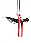 Male circus gymnast tangled in red drapes