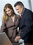 Businessman and businesswoman looking at laptop