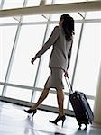 Rear view of businesswoman pulling luggage