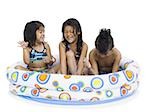 Three young children playing in inflatable pool