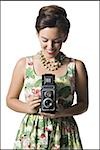 Woman in floral dress holding antique camera