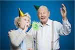 Older couple with noisemakers and party hats