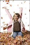 Young girl playing in fallen leaves