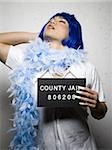 Mug shot of man in drag with blue wig and feather boa