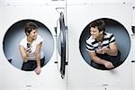 Deux personnes au sèche-linge à la laverie automatique avec les téléphones cellulaires