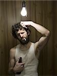 Man standing under light bulb with cigarette and beer bottle