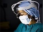 Female doctor in scrubs with head light in surgery