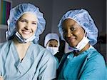 Female surgeon and nurse in scrubs smiling