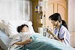 Nurse holding hand of mature woman in hospital bed