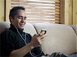 Man sitting on sofa with mp3 player listening to music smiling