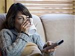 Femme sur le canapé avec une tasse de café et de la télécommande