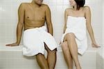 Couple in sauna with towels from neck down