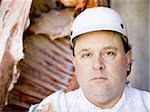 Butcher standing with hanging carcass and knife