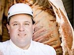 Butcher standing with hanging carcass and knife