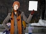 Woman with skates holding blank sign outdoors in winter