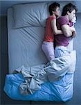 Dormir femme snuggling homme éveillé dans son lit