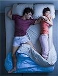 Man stretched out on bed with woman sleeping