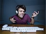 Man with keyboard and headphones playing air guitar
