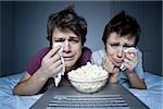 Couple crying with tissue and bowl of popcorn