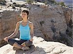 Femme assise Croix legged sur rock en plein air faisant du yoga