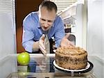 Man in refrigerator reaching for green apple looking at chocolate cake