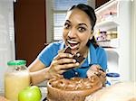 Femme dévorant un gâteau au chocolat de réfrigérateur