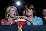 Boy and girl touching hands in popcorn at movie theater